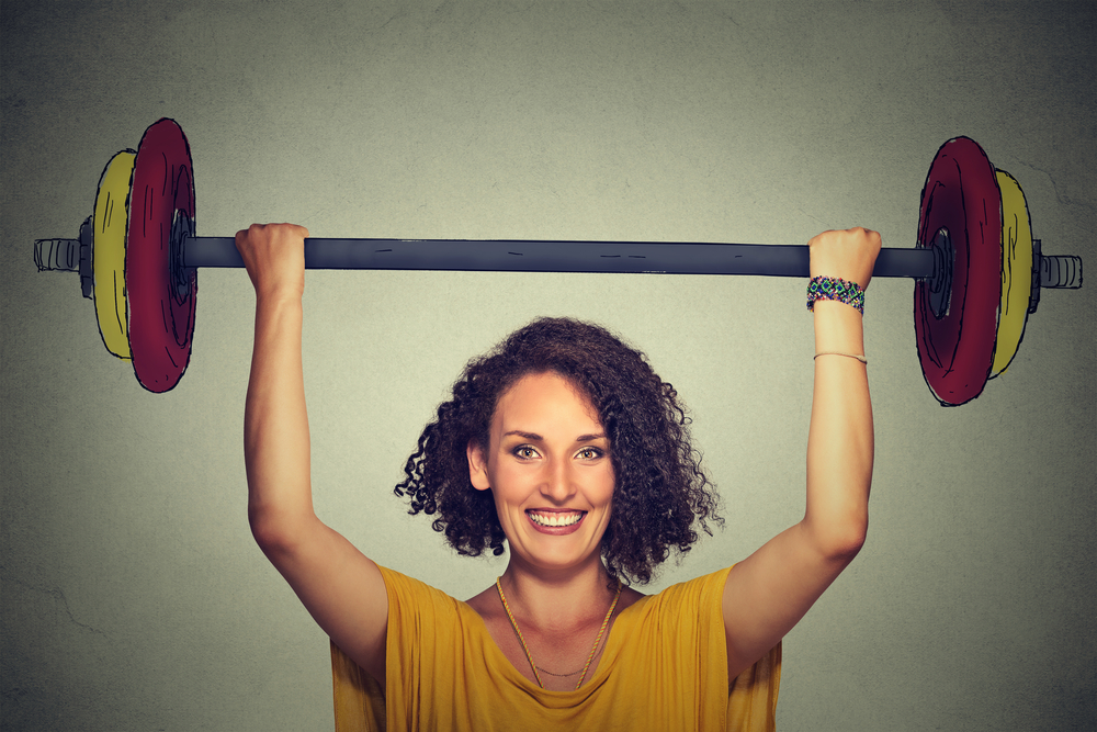 Happy strong young man lifting barbell above head with two hands